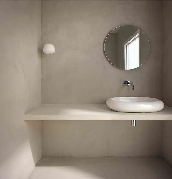 Round basin and mirror against light-toned bathroom walls