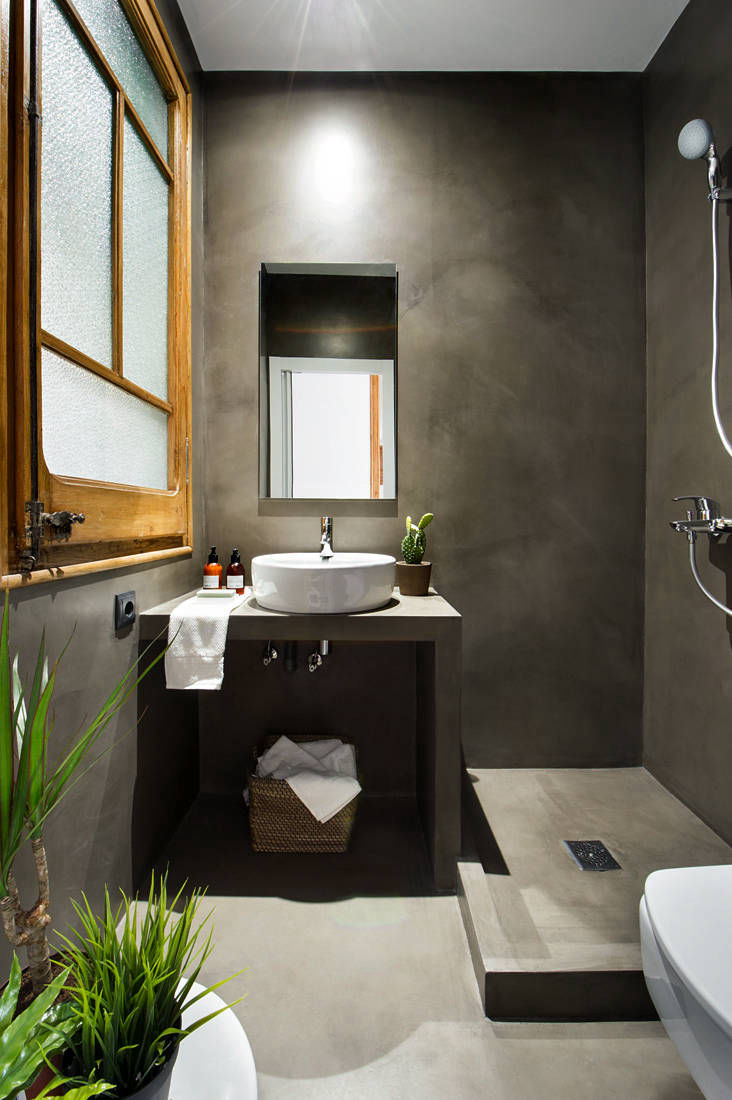 Grey walls and floor in a narrow bathroom with a timber window frame