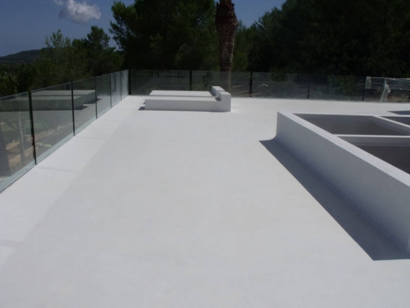 Light grey flooring and seating on a wide terrace with a glass balustrade