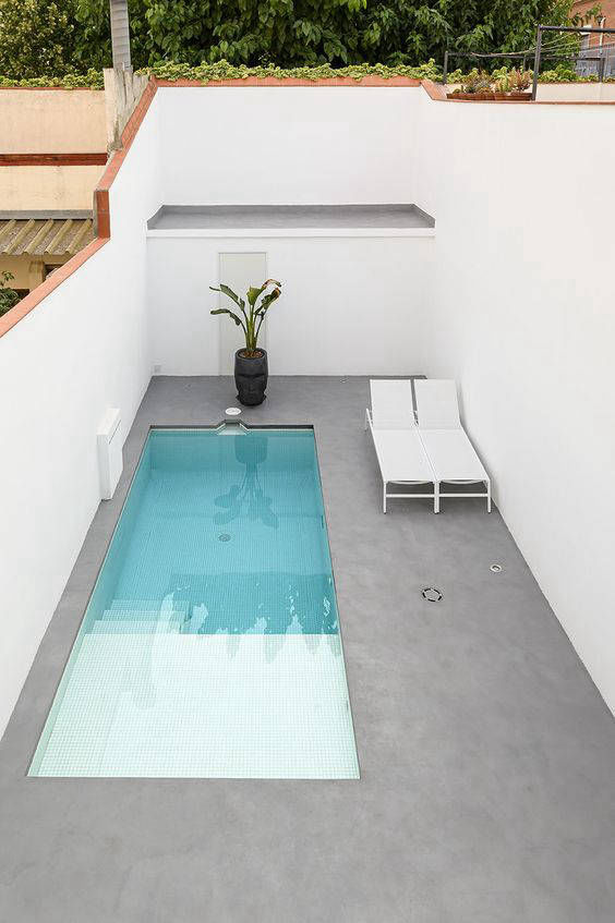 Grey flooring beside a narrow pool enclosed by white walls