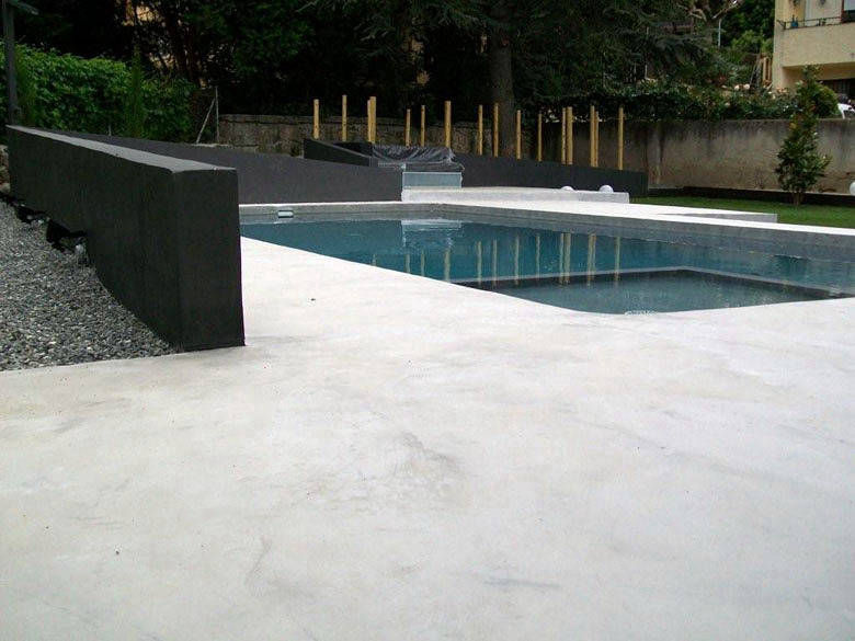 Light grey flooring and a dark wall around a rectangular pool