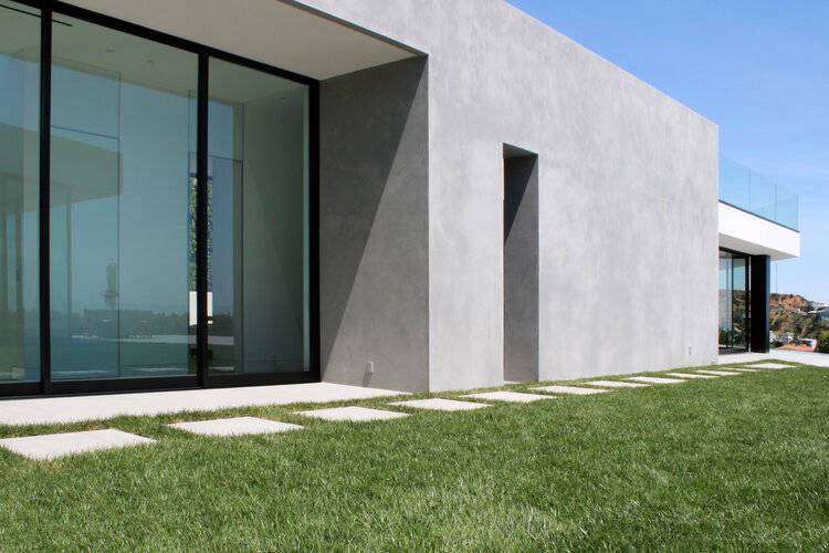 Light grey building façade with wide glazing facing a lawn