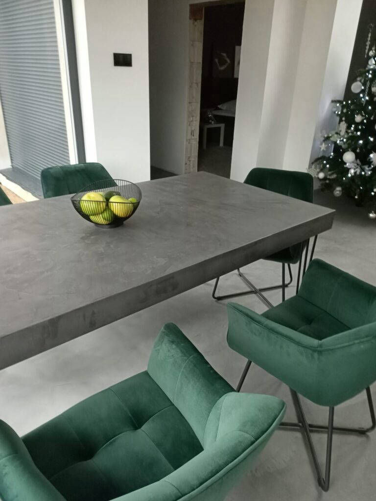 Rectangular grey dining table surrounded by green chairs