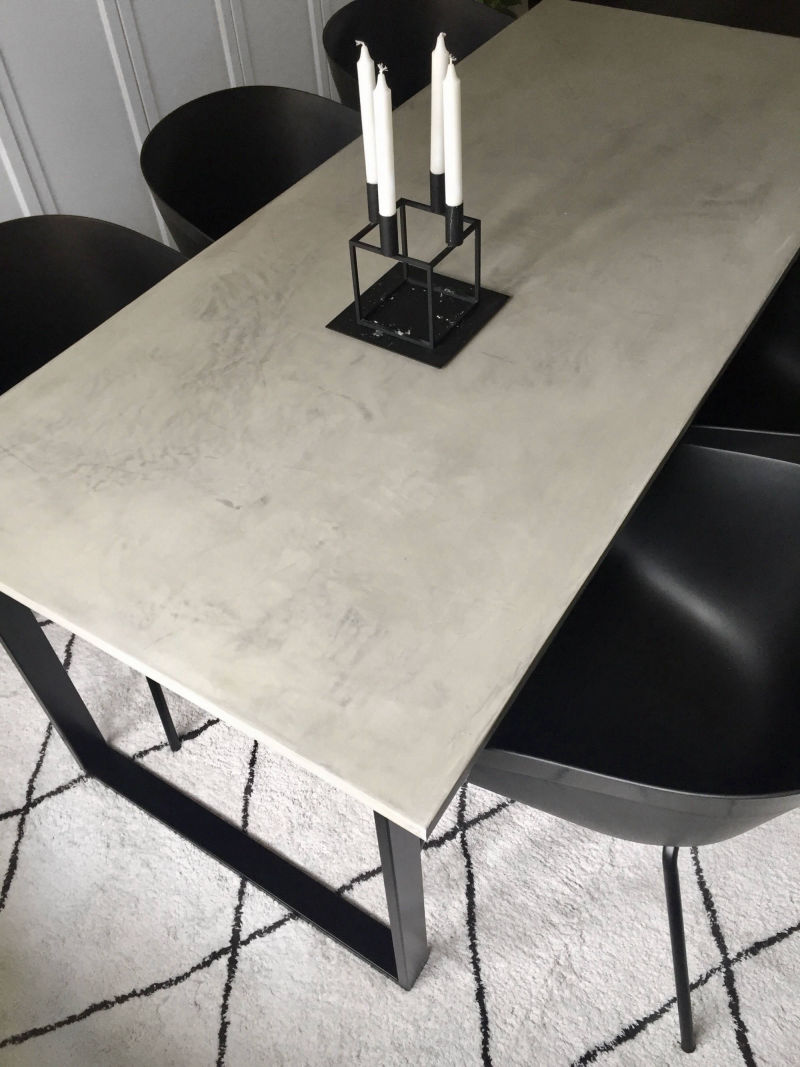 Light grey dining table surrounded by black chairs