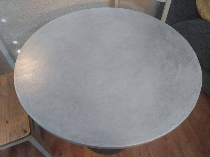 Overhead view of a round grey tabletop above timber flooring