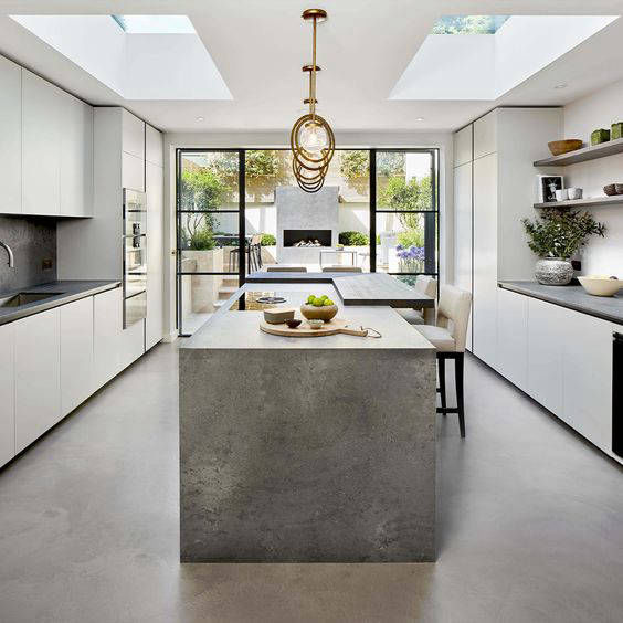 Grey island and light-coloured floor in a kitchen lit by skylights