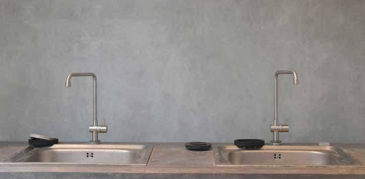 Two sinks and metal taps against a grey wall