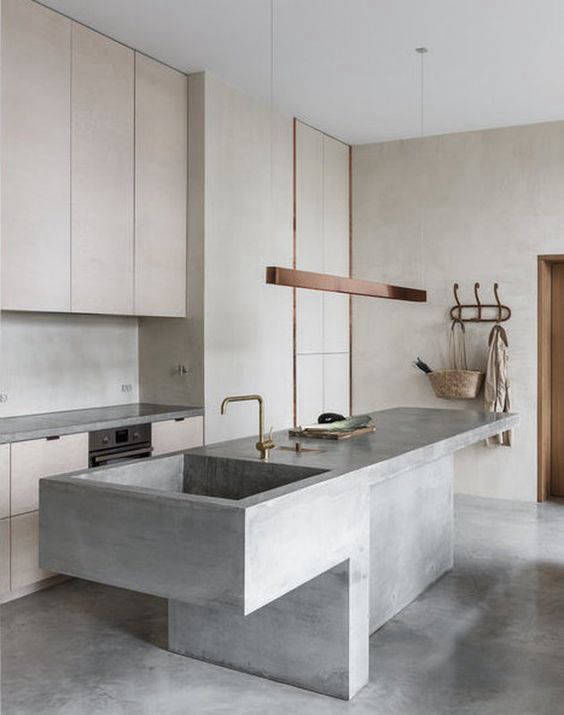 Grey kitchen island and flooring in front of light-coloured cabinets