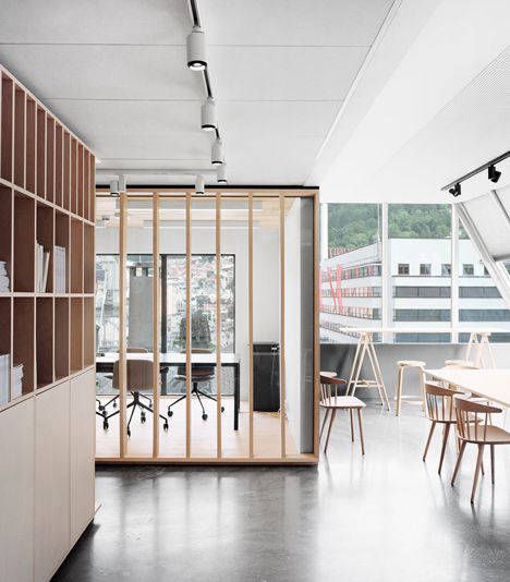 Grey flooring in a workspace divided by timber screens