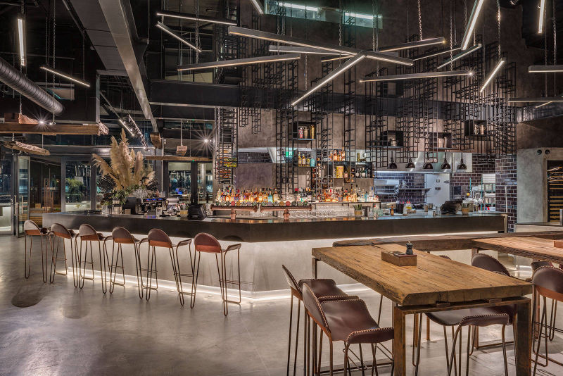 Grey flooring around the bar in a spacious restaurant with exposed services