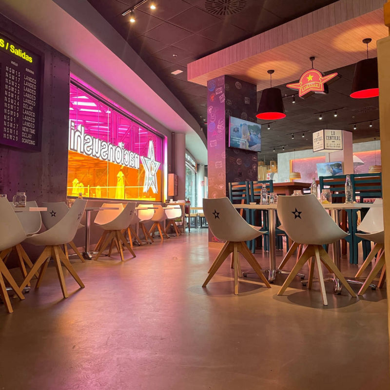 Grey flooring beneath high tables in a restaurant with coloured lighting
