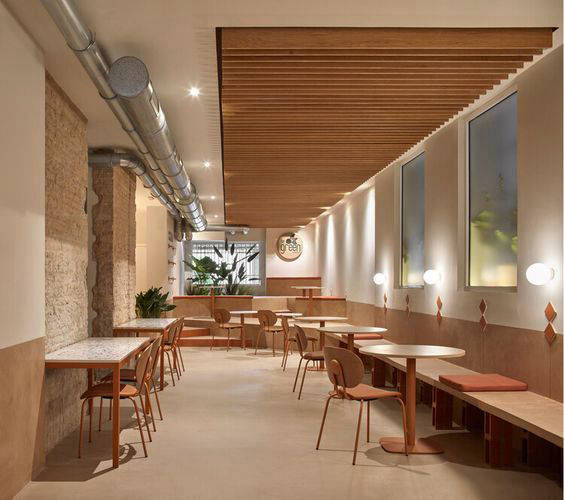 Light-toned walls and floor in a long dining room with a timber ceiling